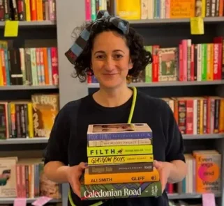 Vicki Shenkin, Bàrd Books owner, holding a pile of books.